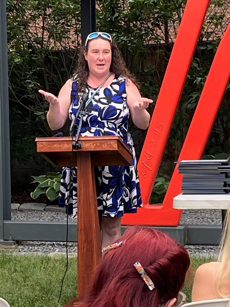 a woman standing at a podium in front of a crowd.